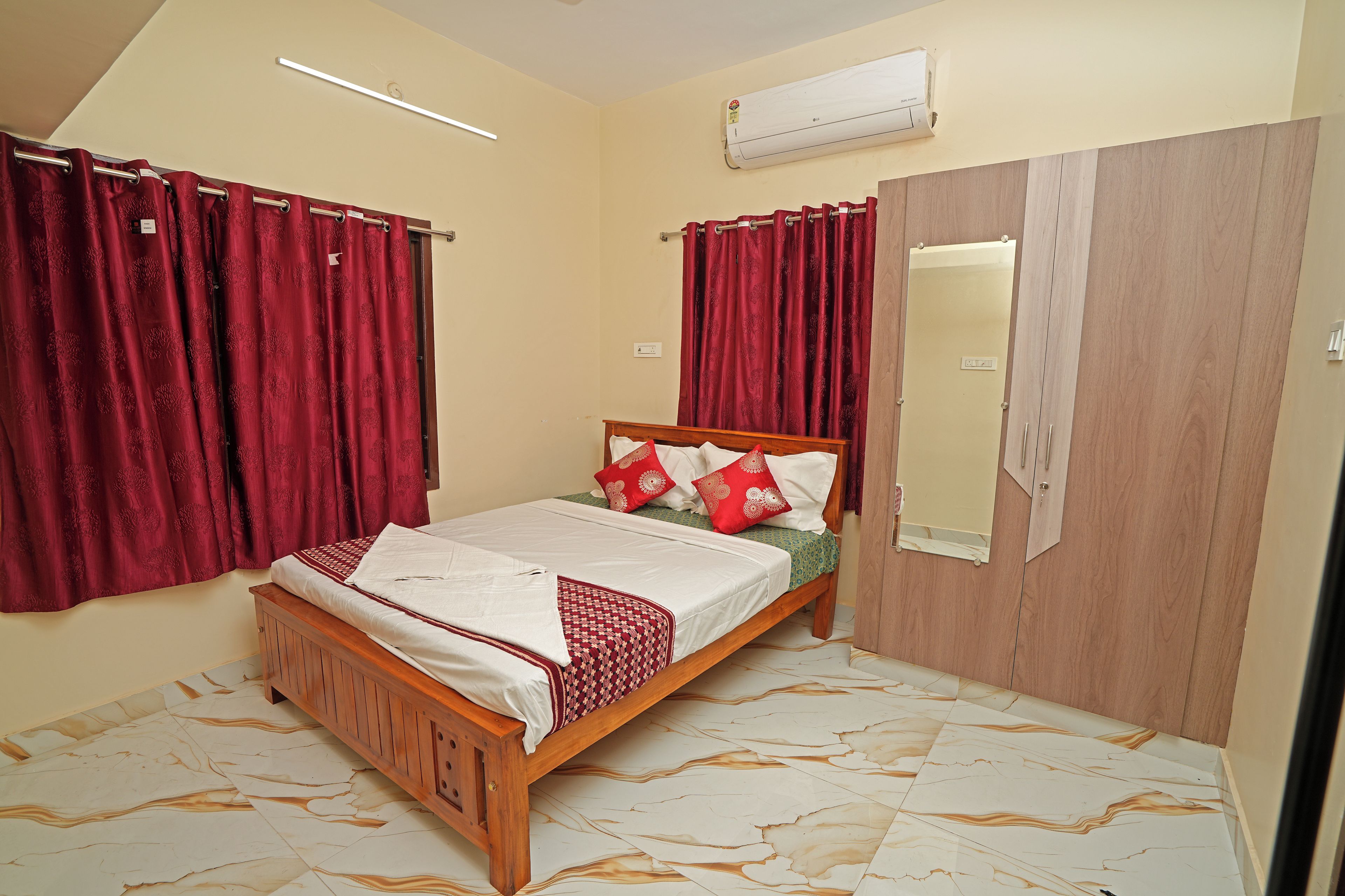A bedroom with a wooden bed, red curtains, a mirror, and a wardrobe.
