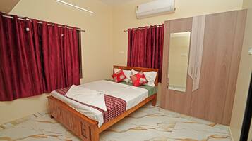 A bedroom with a wooden bed, red curtains, a mirror, and a wardrobe.