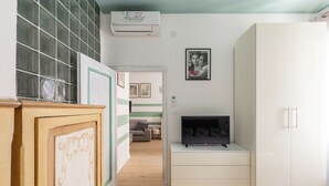 A bedroom with a bed, a wardrobe, a television, and a wall-mounted air conditioner. - Casa 3 Frecce a Corte Isolani by Wonderful Italy (Bologna)