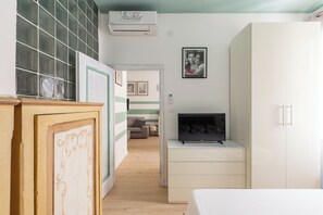 Ein Schlafzimmer mit einem Bett, einem Kleiderschrank, einem Fernseher und einer Wand-Klimaanlage.