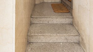 A narrow stairway with a wooden door at the top and a doormat on the steps. - Casa 3 Frecce a Corte Isolani by Wonderful Italy (Bologna)