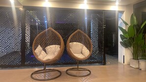 Dos sillas de mimbre con cojines en un interior moderno con paredes estampadas y una planta en maceta.