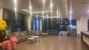 Un moderno vestíbulo de hotel con un sofá, mesas redondas y un coche al fondo.
