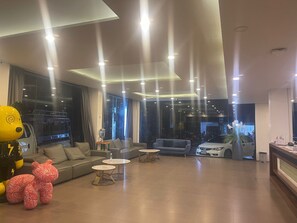 A modern hotel lobby with a sofa, round tables, and a car in the background.