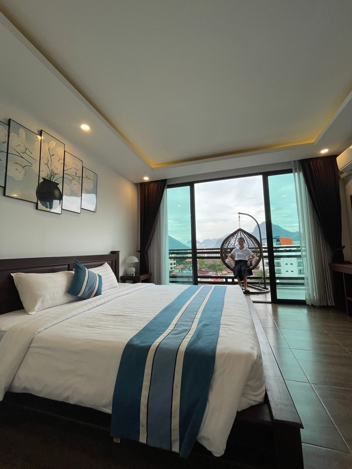 Habitación de hotel con una cama grande, vistas al exterior y un balcón con una silla.