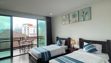 A hotel room with two beds, a balcony, and a city view.