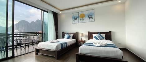A hotel room with two beds, a balcony, and a mountain view.