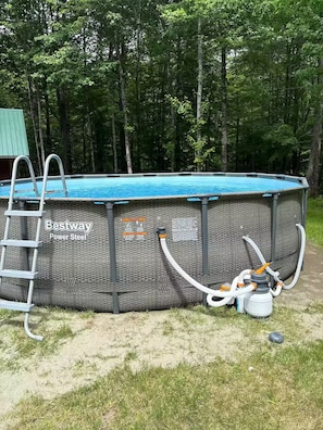 An above-ground swimming pool with a ladder, surrounded by grass and trees. - In the country Fishing hunting boating kayaking. (Mercer)