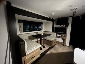 A compact RV interior with a kitchenette, seating area, and a flat-screen TV. - In the country Fishing hunting boating kayaking. (Mercer)