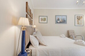 Ein Hotelzimmer mit einem Bett, einem Sessel, einer Lampe und Kunstwerken an den Wänden.