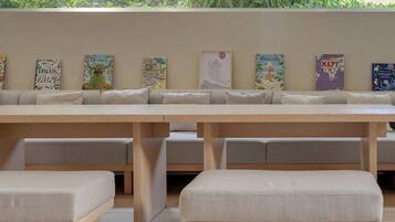 A long wooden bench with cushioned seating and a wall decorated with various colorful posters.