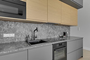 A modern kitchen with a built-in oven, a sink, and a microwave.
