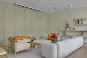 A modern living room with a sofa, two armchairs, a coffee table, and a bookshelf.