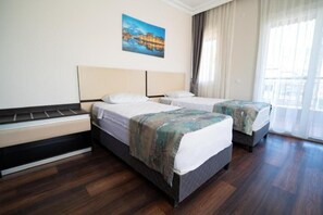 A hotel room with two beds, a large window, and a painting on the wall. - Vega City Apart Hotel (Alanya)