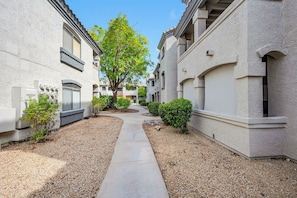 A residential building with a central pathway, small shrubs, and a tree.