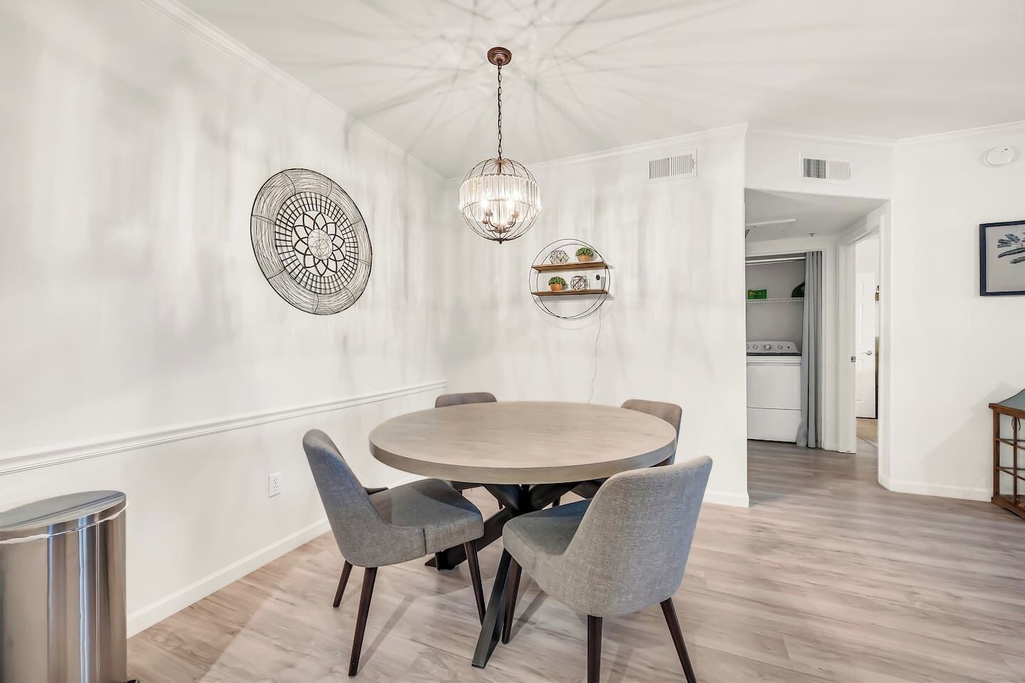 A dining area with a round table and four chairs, a chandelier, and decorative wall art.