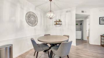 A dining area with a round table and four chairs, a chandelier, and decorative wall art.