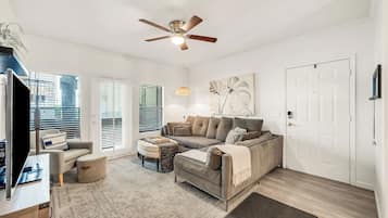 A living room with a sofa, ottoman, and a ceiling fan.