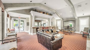 A spacious lobby with a high ceiling, leather sofas, a dining area, and a large mirror.
