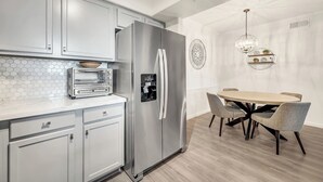 A modern kitchen with a built-in oven, a stainless steel refrigerator, and a dining area with a round table and chairs.