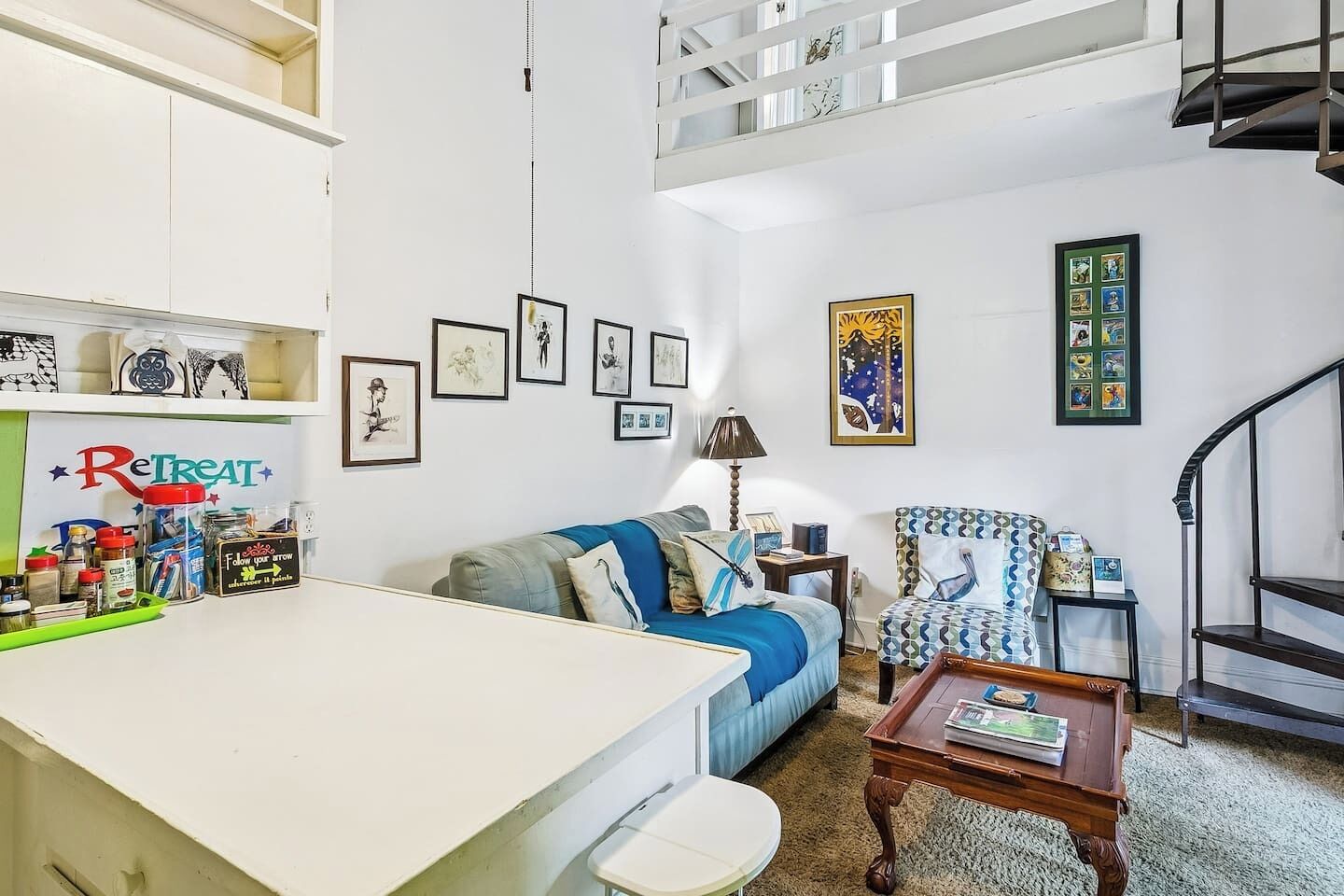 A living room with a sofa, a coffee table, a chair, a small table with a lamp, and a staircase.