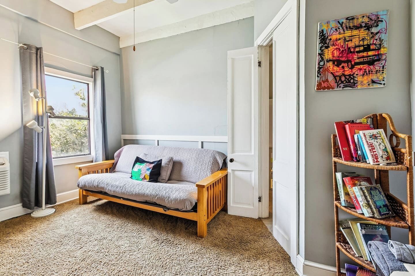 Una habitación con una cama, una estantería y una ventana.