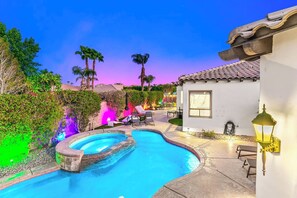 A swimming pool with a curved design, surrounded by a patio area with lounge chairs and a small building with a tiled roof. - All Inclusive- Nine Cities One Oasis/Game Room (Indio)