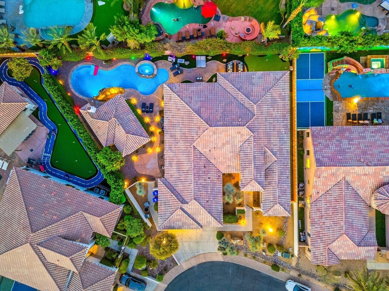 An aerial view of a resort with multiple swimming pools, outdoor seating areas, and a well-maintained landscape.