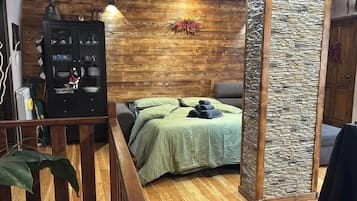 Une pièce avec un lit, une armoire, une plante et un mur en pierre.