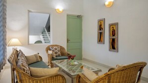 Una habitación con muebles de mimbre, una mesa de vidrio y una puerta verde.