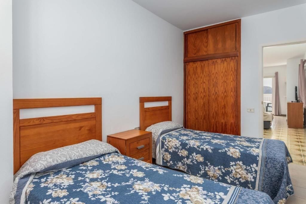Een slaapkamer met twee houten bedden, een nachtkastje en een kledingkast.