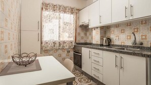A compact kitchen with white cabinets, a granite countertop, and patterned tile flooring. - Edificio Los Playeros (Arona)