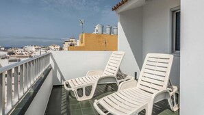 A balcony with two white lounge chairs, a tiled floor, and a view of the cityscape. - Edificio Los Playeros (Arona)