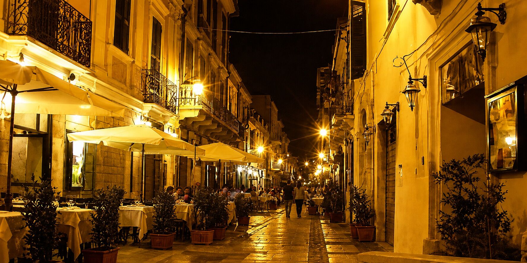 Una calle estrecha bordeada de mesas y sillas al aire libre, lo que sugiere un área de comedor.