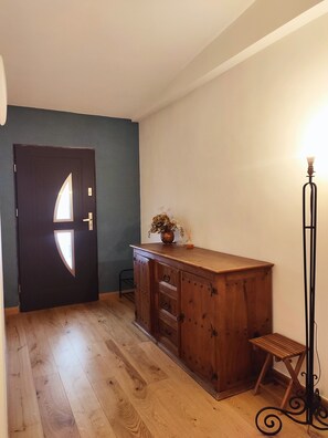 Ein Zimmer mit einem Holzkabinett, einer Tür mit einzigartigem Design, einem kleinen Tisch und einer Stehlampe.