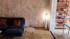 Una sala de estar con un sofá, una mesa redonda y una pared con estanterías que contienen platos y vasos.