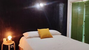 Un dormitorio con una cama, una mesita de noche con lámpara y una puerta verde.