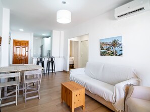 Ein modernes Wohnzimmer mit einem weißen Sofa, einem Holztisch und einem Essbereich mit einem Holztisch und Stühlen.