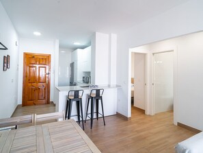 Eine moderne Küche mit weißen Schränken, einem Edelstahl-Kühlschrank und zwei schwarzen Barhocker.
