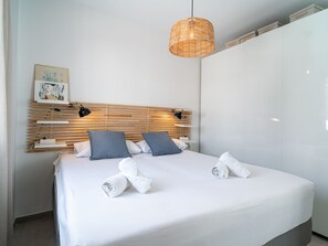 A neatly made bed with white linens and two rolled towels, a wooden slatted headboard, and a hanging woven light fixture. - Casa Solera by Casasol by Interhome (Nerja)