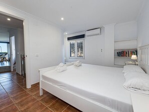 A bedroom with a large bed, a bedside table with a lamp, a window with decorative glass, and a bookshelf. - Stella Maris Suite by Casasol by Interhome (Nerja)