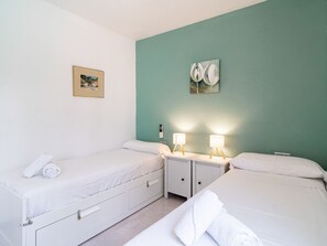Ein Doppelzimmer mit zwei Betten, einem Nachttisch mit Lampen und Bildern an den Wänden.