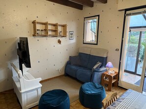 Ein Wohnzimmer mit einer Couch, Hocker, Holzregalen, einem Fernseher und einem Fenster mit Blick.
