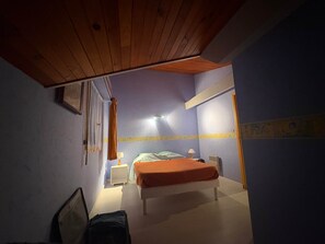 A bedroom with a bed, bedside tables, a nightstand, a hanging curtain, and a ceiling with wooden beams. - Lou Pignada—Veranda, private garden—bicycles available, and the beach is 6 minutes away (Mimizan)