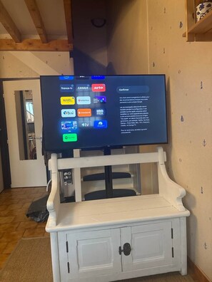 Ein Fernseher an einem weißen Schrank, dessen Bildschirm verschiedene Logos von Streaming-Diensten zeigt.