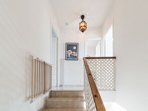 A staircase with a wooden handrail, a wall-mounted light fixture, and a framed picture. - Apartment  by Interhome (Nerja)
