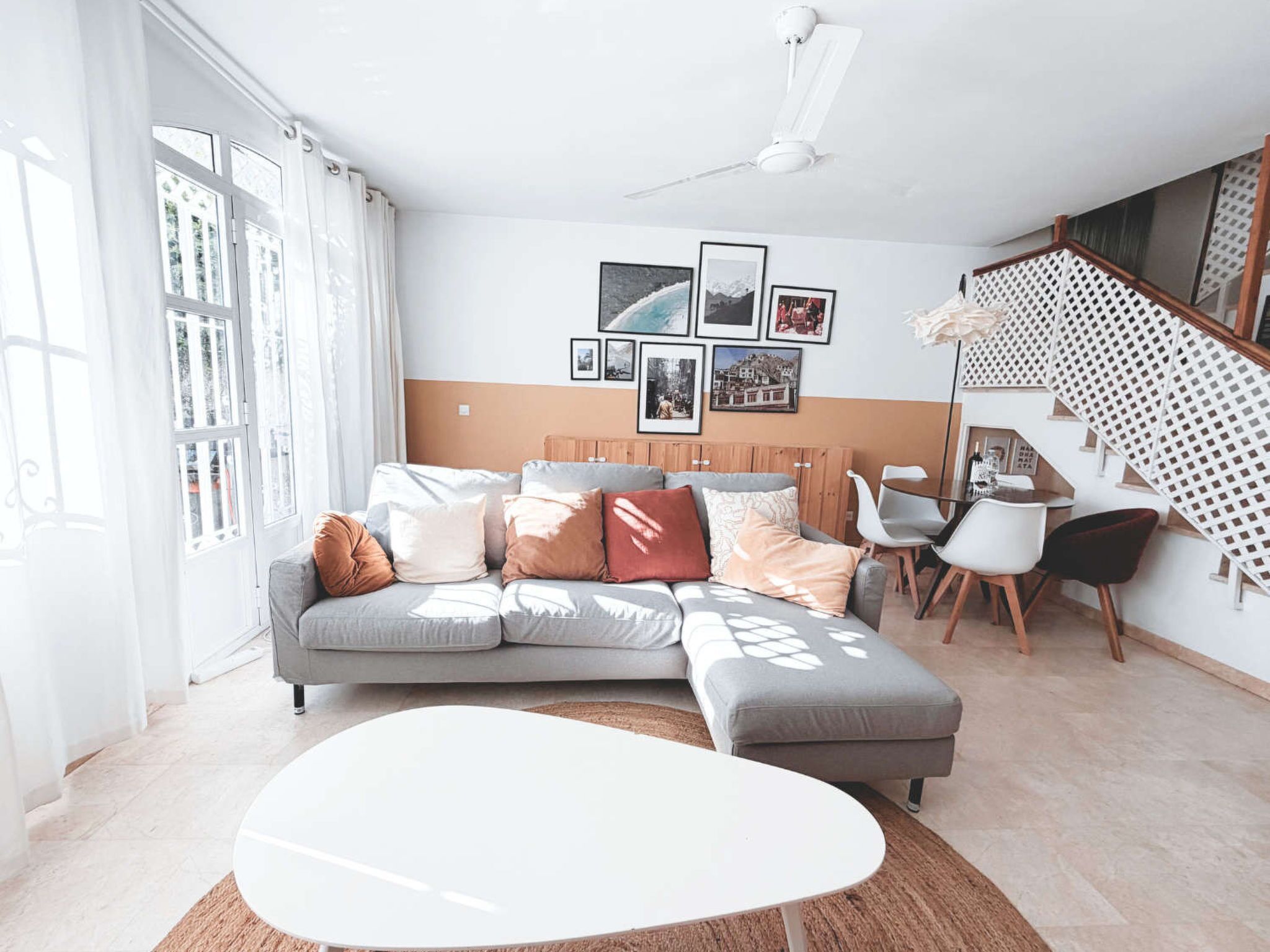 Un salon moderne avec un canapé d’angle gris, une table basse blanche et un escalier doté d’une rampe blanche.