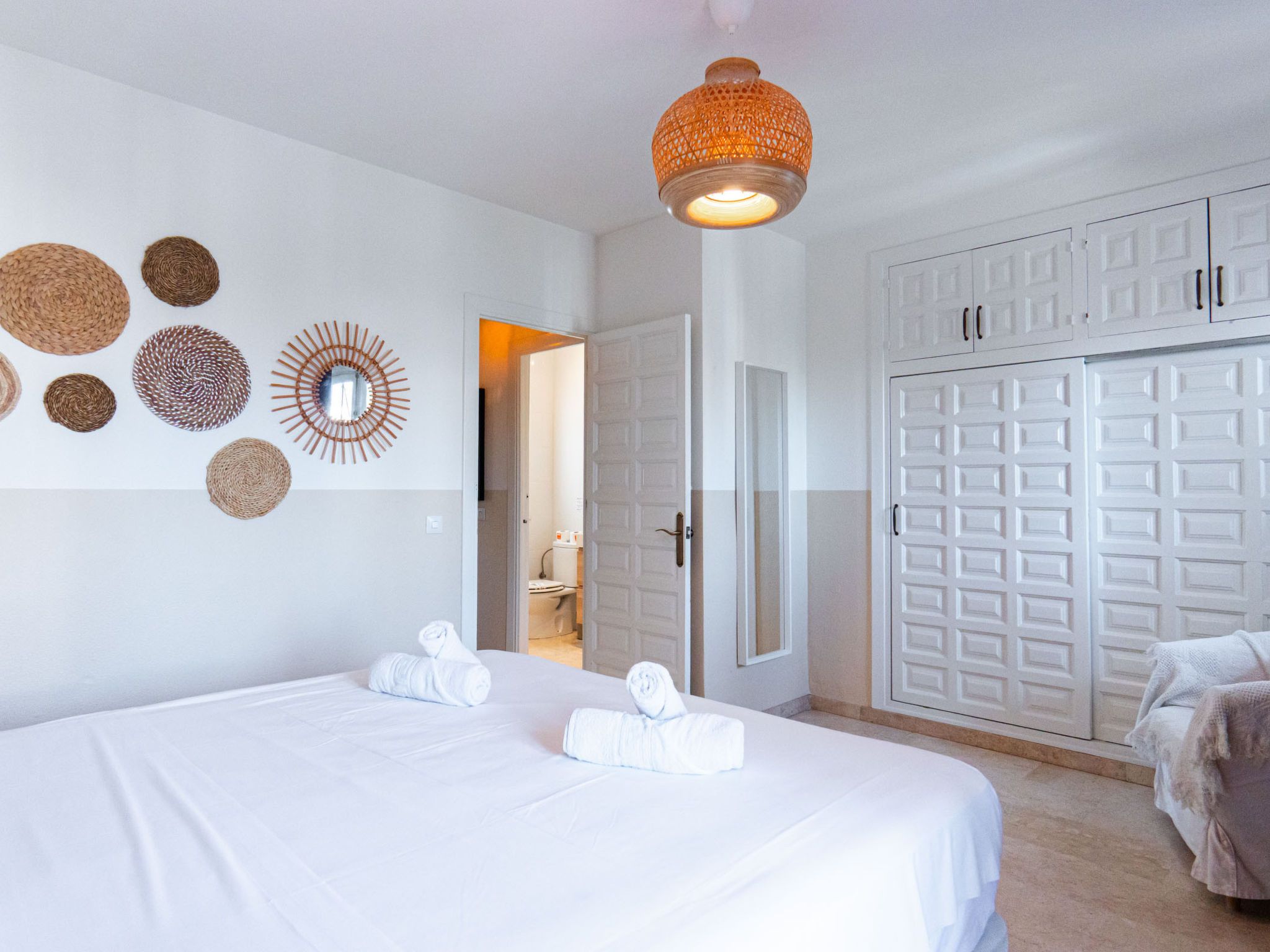 Une chambre d’hôtel avec un lit, une armoire et une salle de bain, visibles à travers une porte ouverte.