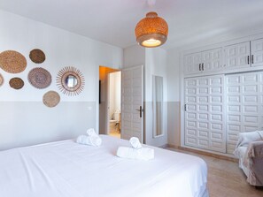 Ein Hotelzimmer mit einem Bett, einem Kleiderschrank und einem durch eine offene Tür einsehbaren Badezimmer.