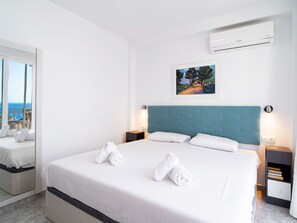 Habitación de hotel con una cama, un cuadro, equipo de aire acondicionado y vista al mar a través de una ventana.
